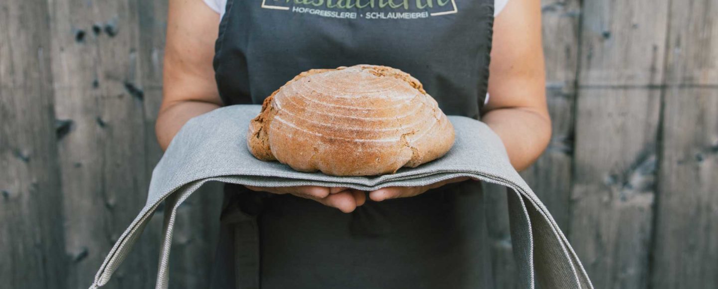 Die Haslacherin - Katharina mit Schürze zeigt frisches Brot